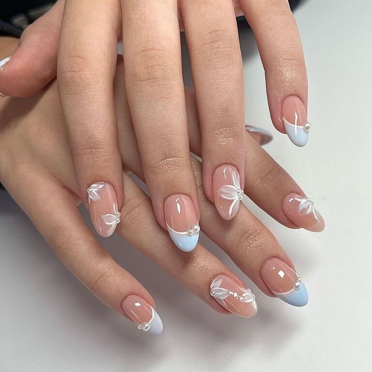 Sophisticated Soft Blue French Tip Nails with Floral Patterns and Pearl Accents.