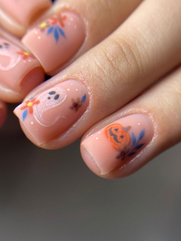 Whimsical Halloween Nail Design: Soft Nude Base with Charming Ghosts, Pumpkins, and Floral Accents