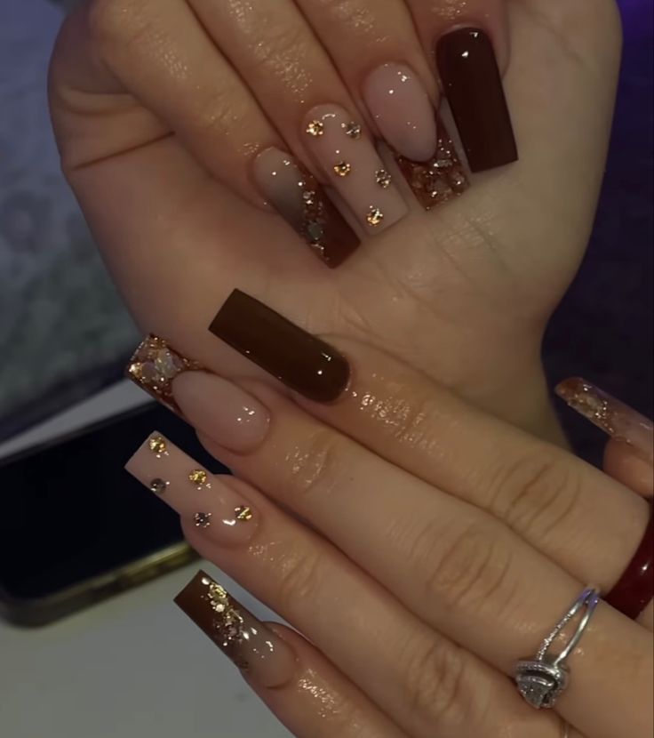 Chic and Playful Nail Design: Elegant Brown and Nude with Golden Accents and Heart Embellishments.