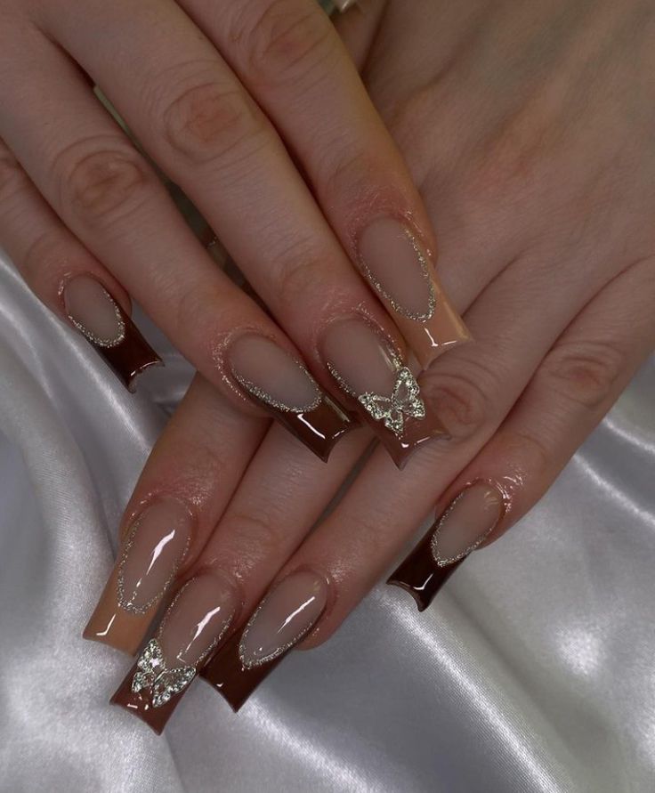 Sophisticated Nude and Deep Brown Nail Design with Glamorous Silver Accents and Playful Butterfly.