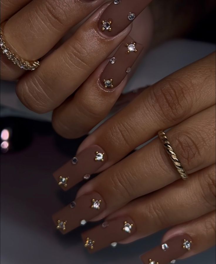 Glamorous Nude Nail Design Accentuated with Rhinestones and Star Embellishments.