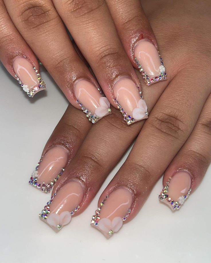 Chic Nude Nail Design with Rhinestone Accents and Floral Embellishments.