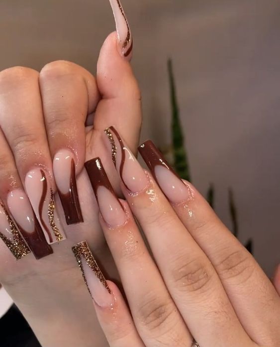 Chic Brown and Nude Nail Design with Glamorous Gold Accents and Wavy Patterns.