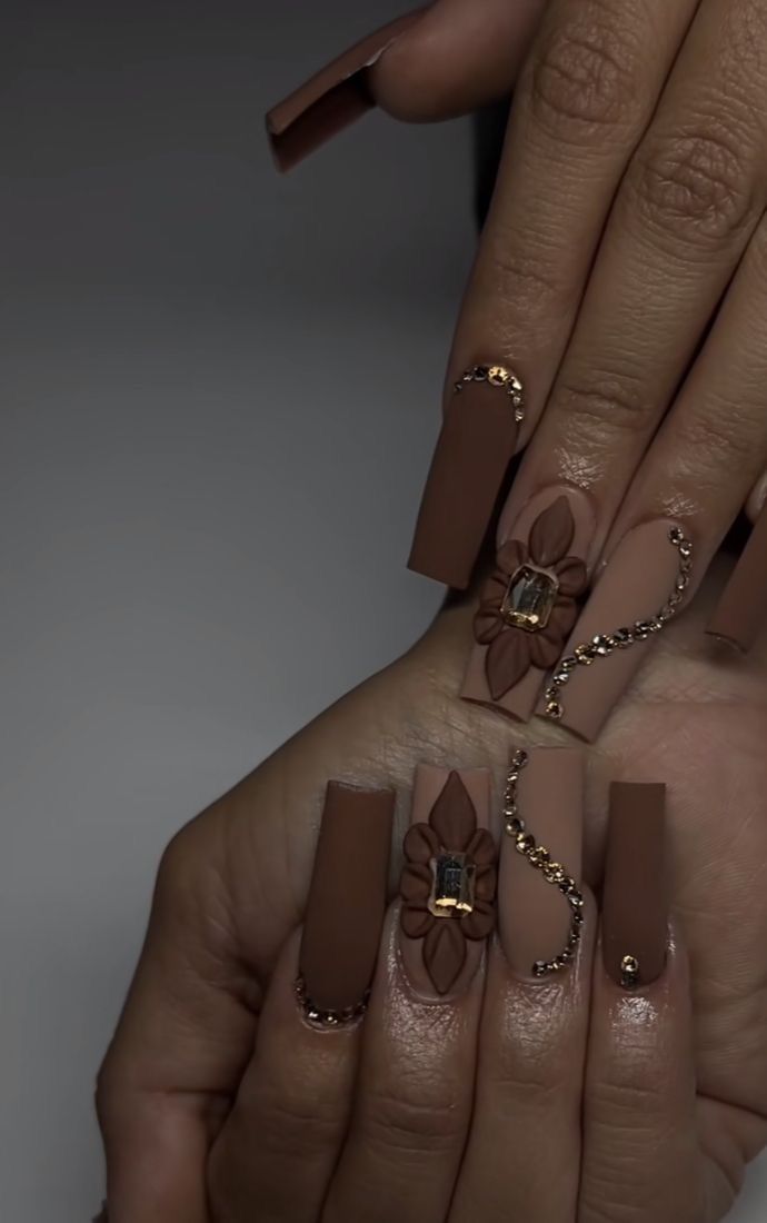 Sophisticated Brown Nail Design with Textured Floral Embellishments and Gold Detailing.