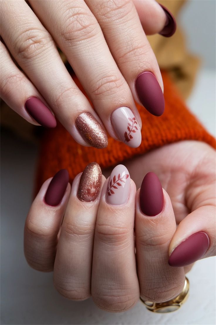 Sophisticated Burgundy Matte Nail Design with Gold Accent and Floral Motifs.