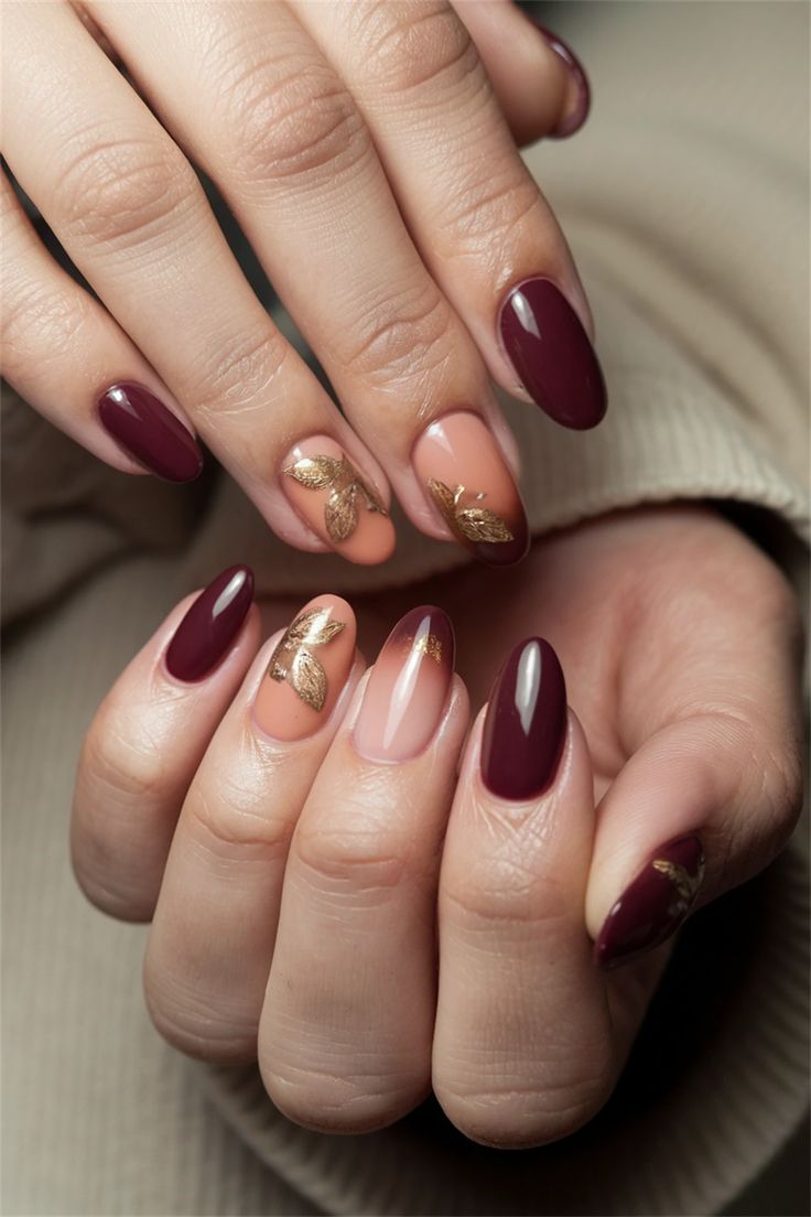 Elegant Maroon and Nude Nail Design with Glamorous Gold Leaf Accents.