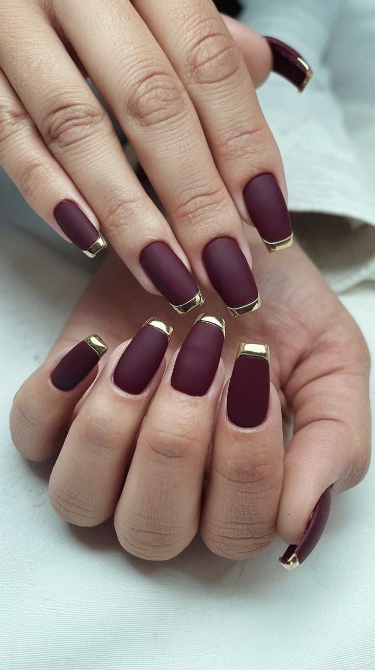 Sophisticated Matte Burgundy Nails with Glossy Gold Tips: A Chic Design for Any Occasion.