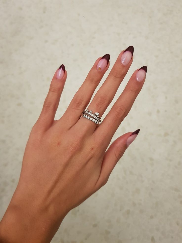 Elegant Ombre Nail Design: Soft Pink and Deep Burgundy Tips with Intricate Jewelry.