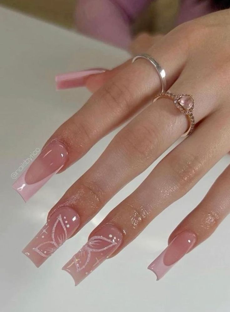 Elegant Soft Nude Nail Design with Intricate White Floral Patterns on Long Square Tips.