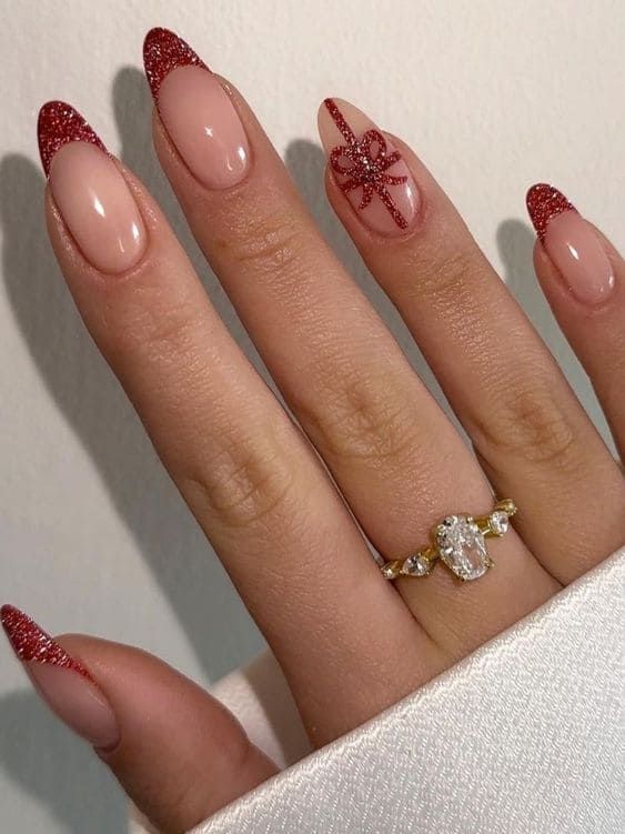 Sophisticated Festive Nail Art: Nude Base with Sparkling Red French Tips and Decorative Bow.