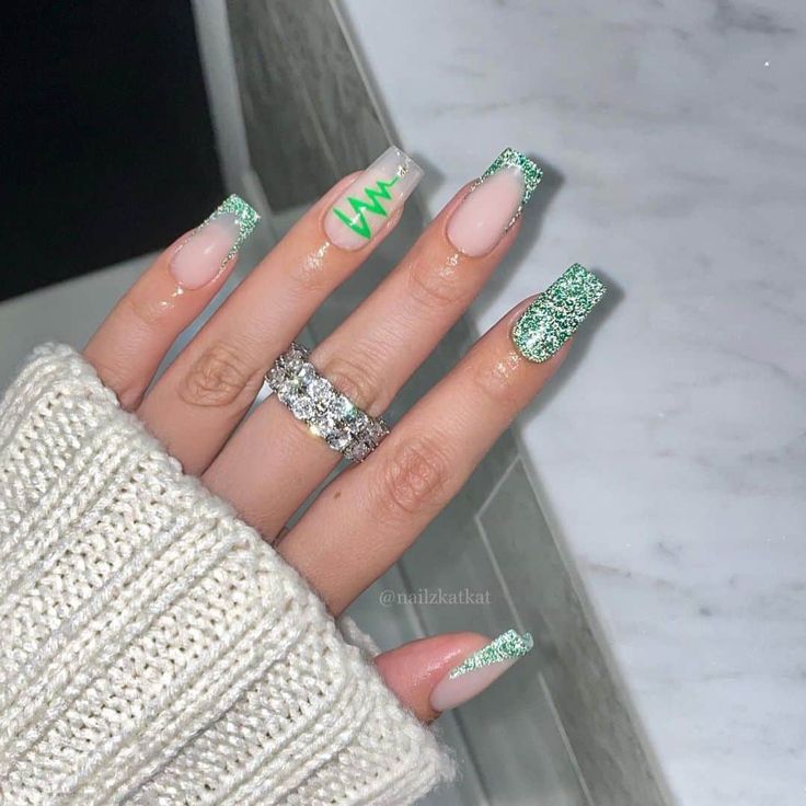 Trendy Nail Design: Elegant Nude & Vibrant Green with Glitter Accents and Bold Graphics.