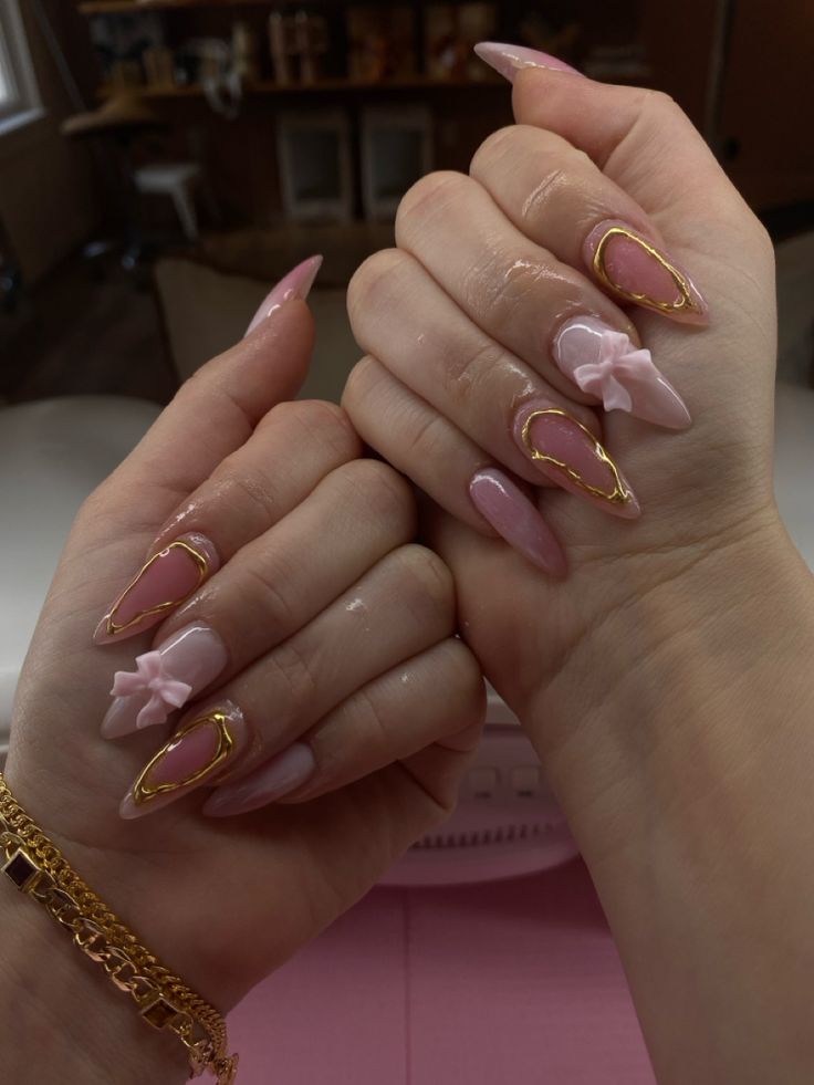 Luxurious Playful Nail Design with Soft Pink, Glossy Finishes, Gold Accents, and Bow Details.