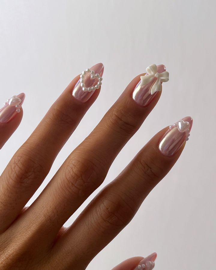 Whimsical yet Sophisticated Soft Pink Nail Design with Pearlescent Finish and Intricate Embellishments.