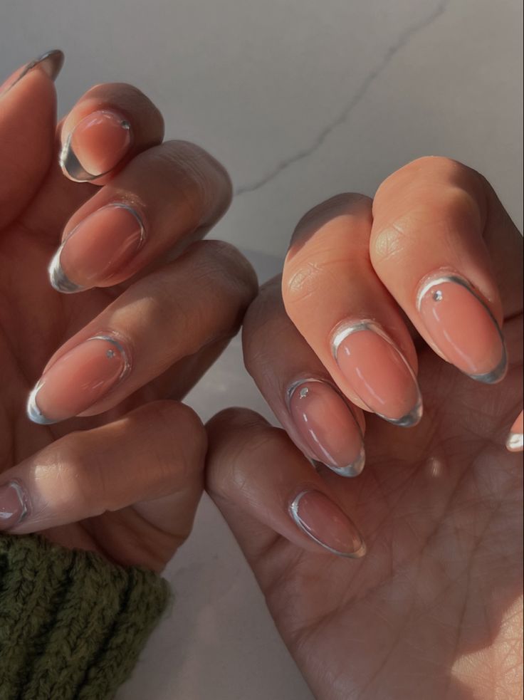 Chic Nude Nails with Peach French Tips and Subtle Gem Embellishments.