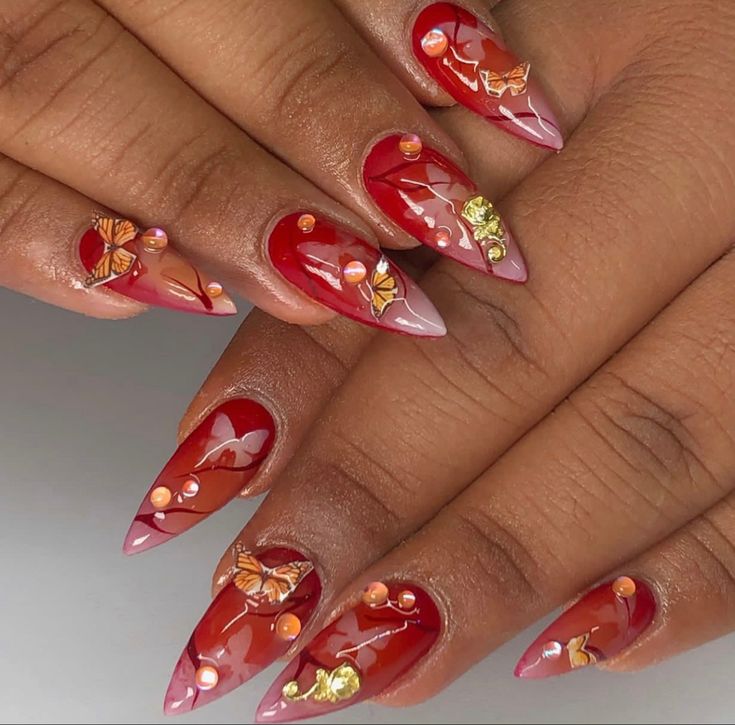 Whimsical Nail Design with Vibrant Red and Soft Pink Hues, Butterfly Patterns, and Elegant Gemstone Accents.