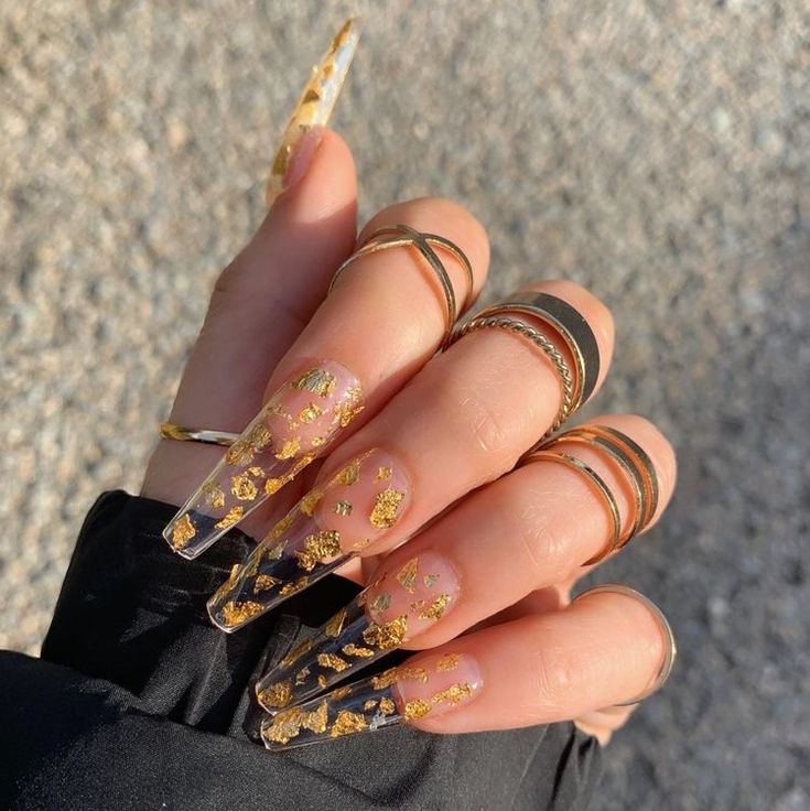 Elegantly Glamorous Acrylic Nails with Gold Flakes and Delicate Rings