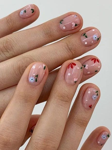 Whimsical Floral Nail Design with Delicate Blossoms on Soft Pink Background.