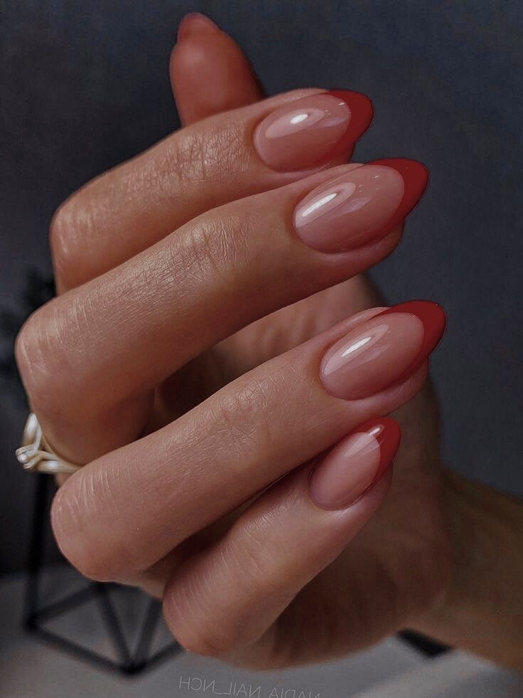 Chic Almond-Shaped Nail Design: Soft Nude Base with Striking Red Tips.