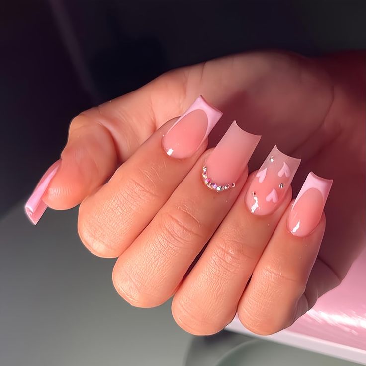 Elegant Soft Pink Nail Design with Intricate Embellishments and Glossy Finishes.