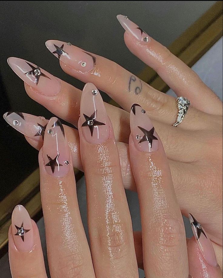 Chic Translucent Pink Nail Design with Bold Black Stars and Rhinestones.