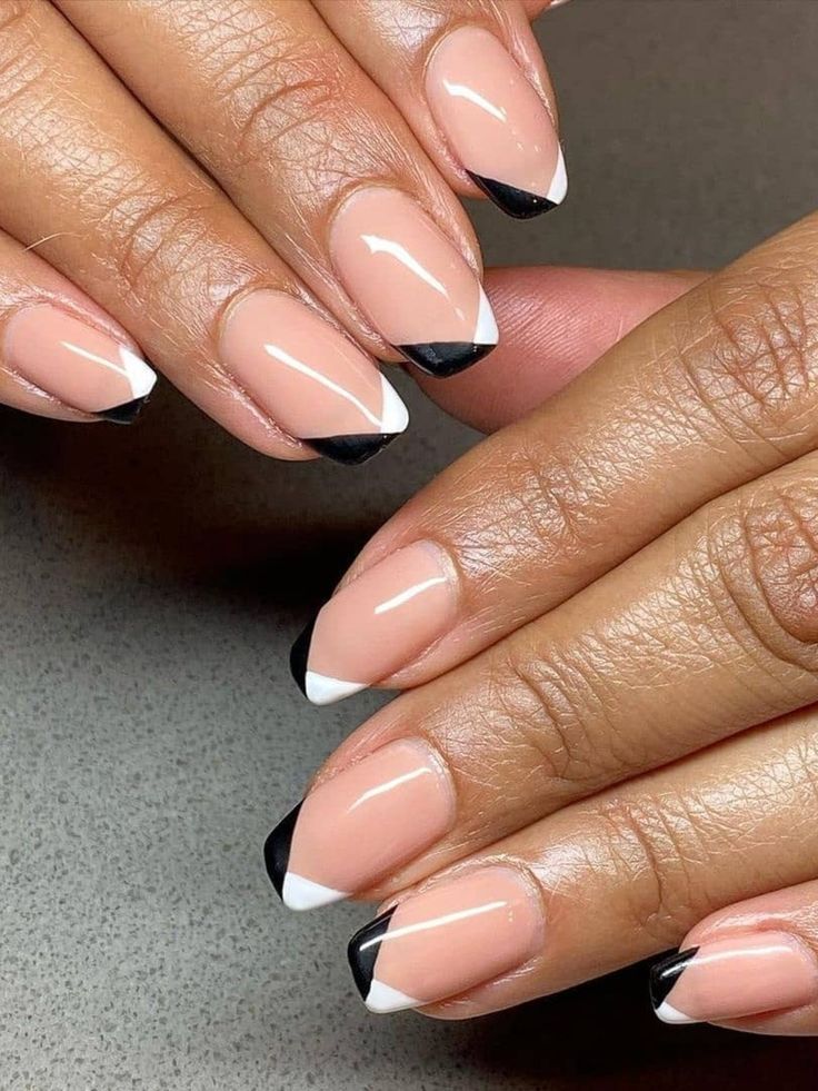 Edgy Modern French Tip Nail Design with Triangular Black and White Tips on a Nude Base.