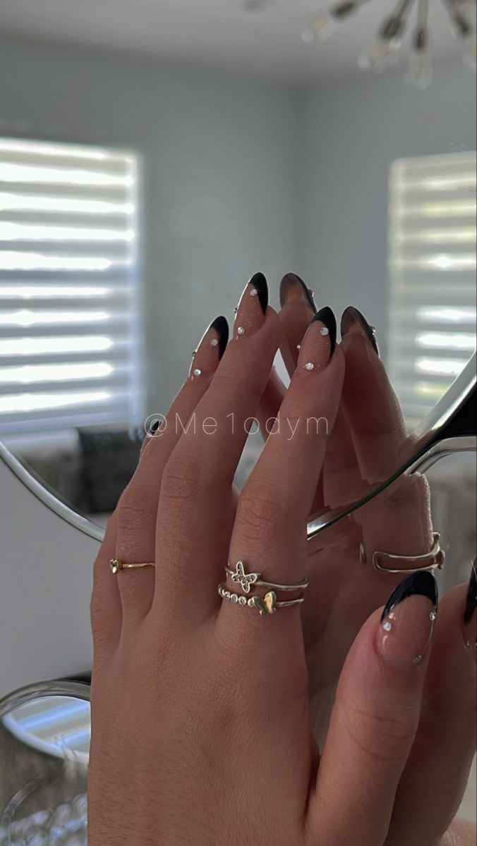 Sophisticated Black French Tip Nail Design with Silver Accents and Delicate Rings.