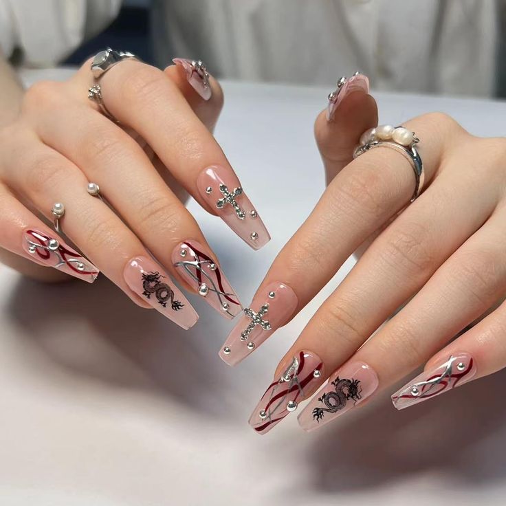 Sophisticated Nude Nail Design with Black Floral Patterns and Glamorous Embellishments.