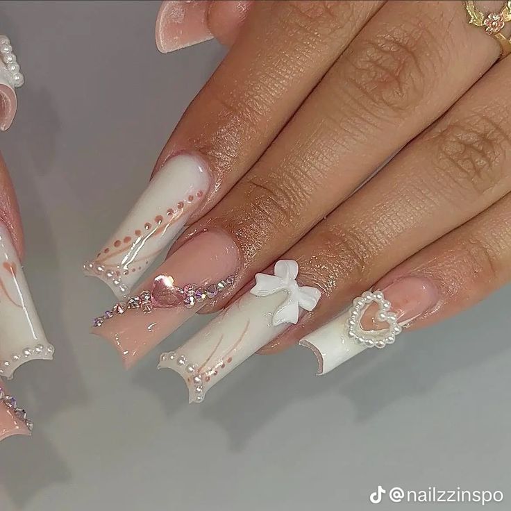 Sophisticated Nail Design with Soft Pink and White Shades, Intricate Patterns, and Charming Embellishments.