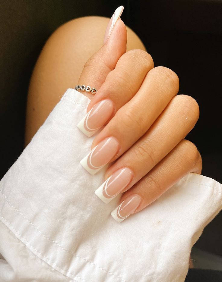 Sophisticated Modern French Manicure: Soft Nude Base with Chic White Tips and Elegant Swirling Accents.