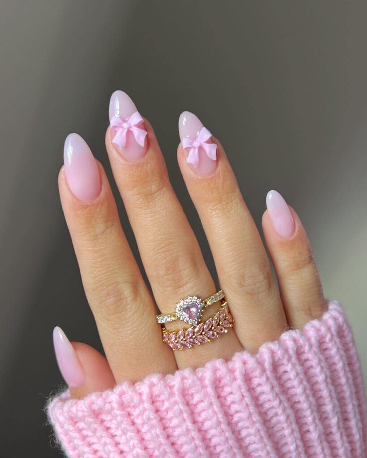 Charming Soft Pink Nail Design with Delicate Bows and Shimmering Rings.