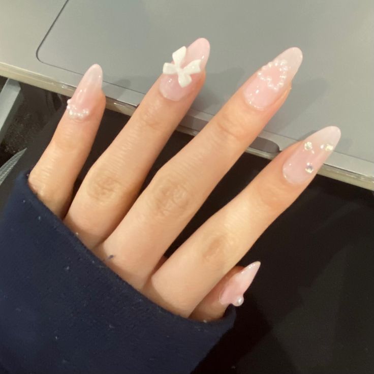 Delicate Soft Pink Nails Elegantly Adorned with White Bows and Gemstones