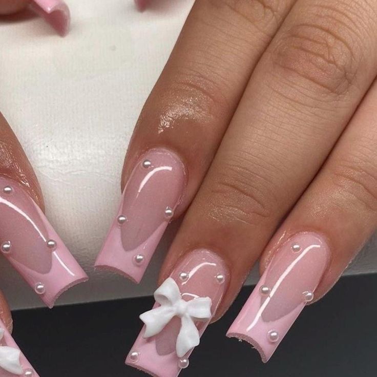 Elegant Pink Nails with Glossy Finish, Pearls, and Feminine Bow Design.