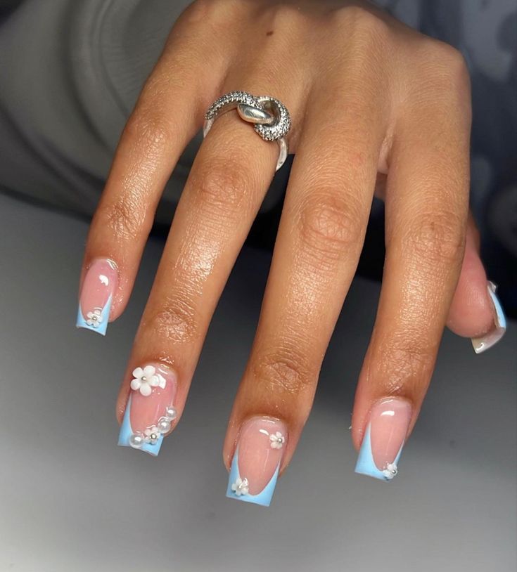 Elegant Floral Accent Nail Design with Soft Pink Base and Pastel Blue French Tips for a Spring-Inspired Look.