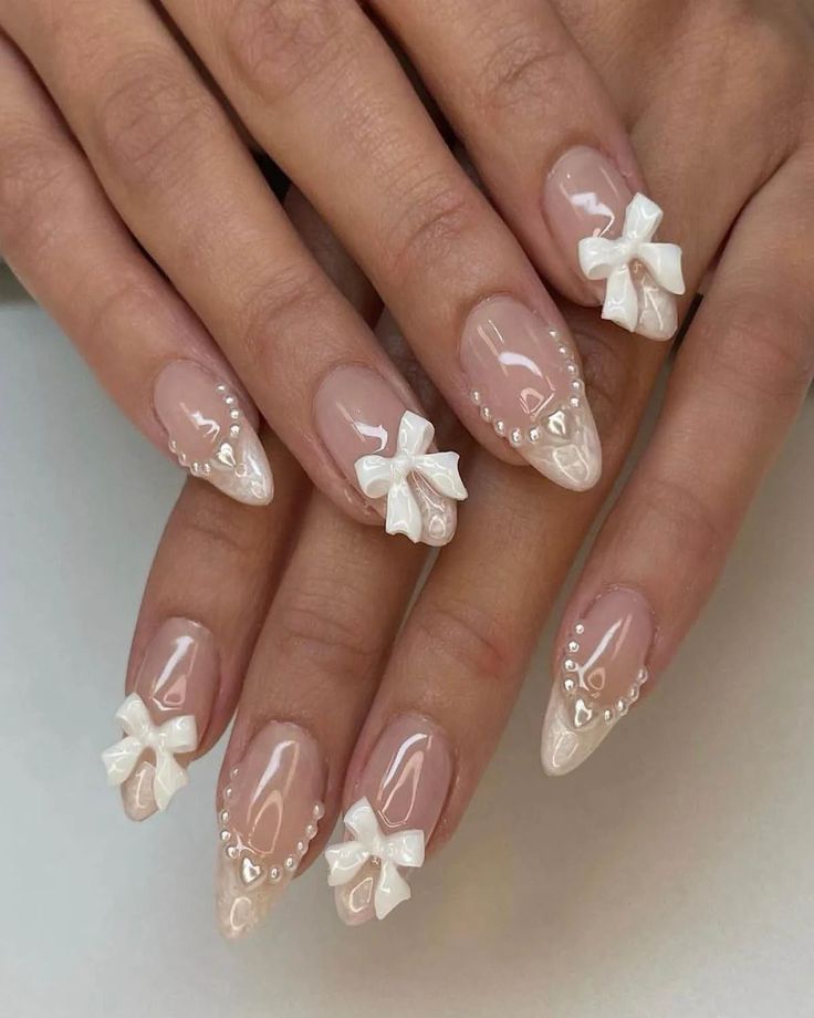 Charming and Sophisticated Glossy Nail Design with Neutral Shades and Delicate Bow Embellishments.