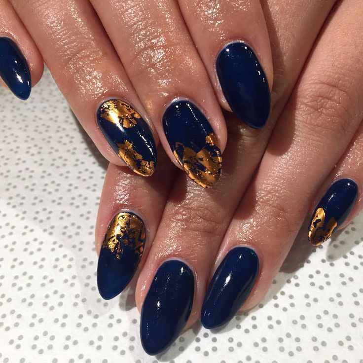 Elegant Navy Blue Nail Design with Gold Leaf Accents for a Chic Look.