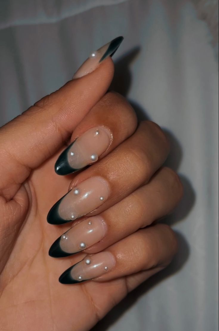 Sophisticated Nail Design: Sheer and Dark Green Tips with Glossy Nude Backgrounds and Pearl Accents.