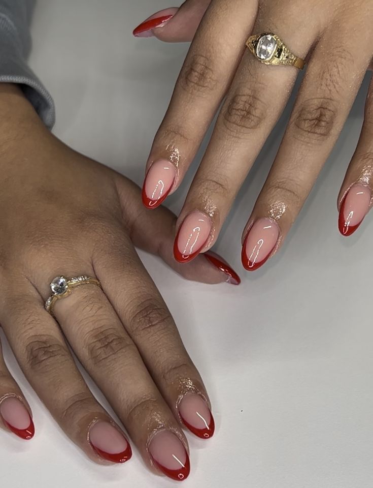 Chic French Tip Nail Design: Nude and Bold Red Elegance with Almond Shape and Delicate Rings.