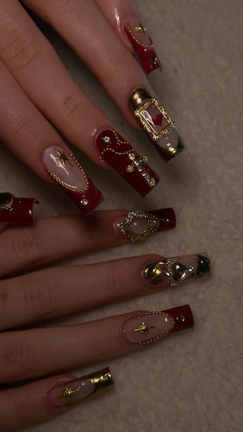 Luxurious Deep Red and Nude Nail Design with Gold Embellishments for a Glamorous Look.