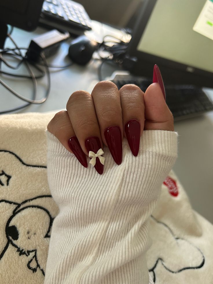 Elegant Almond-Shaped Burgundy Nails with Whimsical White Bow Accent