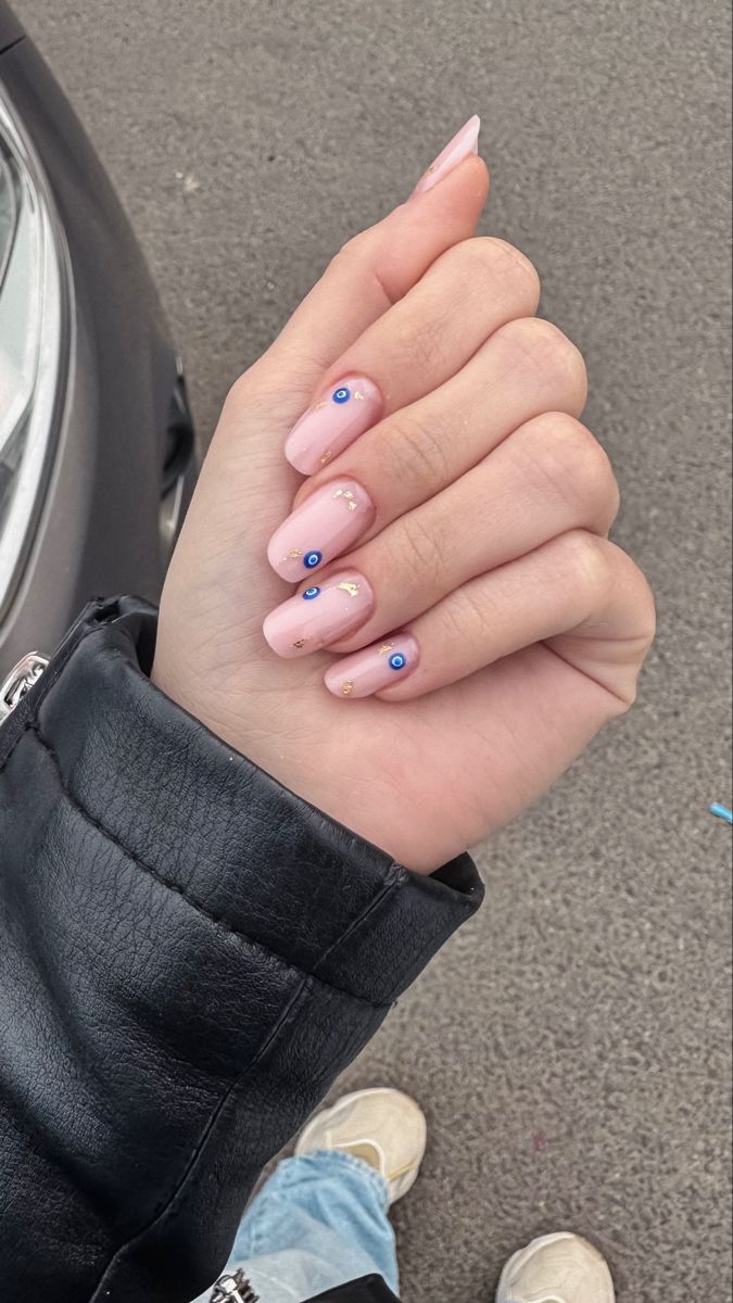 Chic Soft Pink Nails with Gold Accents and Playful Blue Gems.