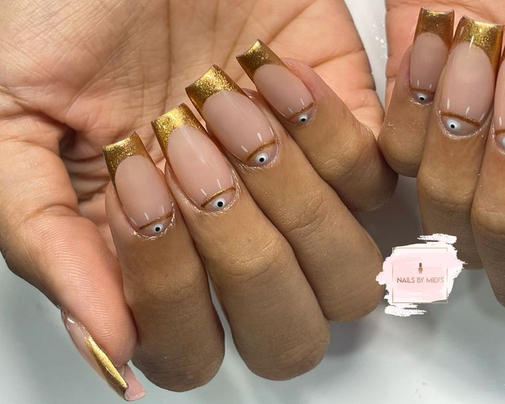 Elegant Chic Nail Design with Square Tips, Gold Accents, and Playful Eye Embellishments.