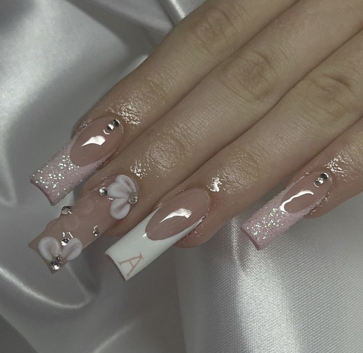 Sophisticated Soft Pink Nail Design with Floral Accents and Sparkling Rhinestones.