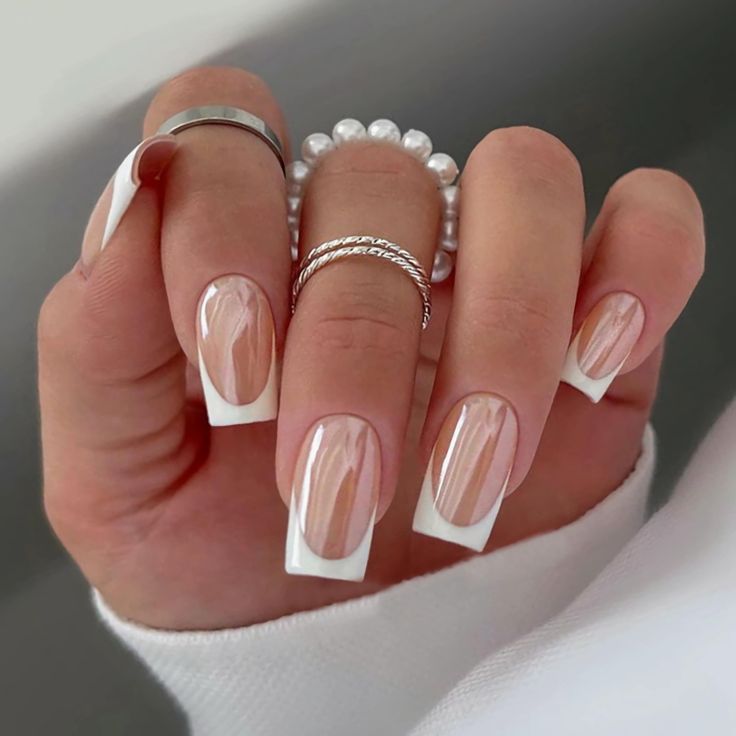 Chic Almond-Shaped Nails: A Modern Nude and White French Manicure with Ombre Depth and Elegant Accessories.