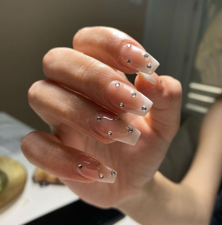 Sophisticated French Tip Nail Design with Glamorous Metallic Studs.