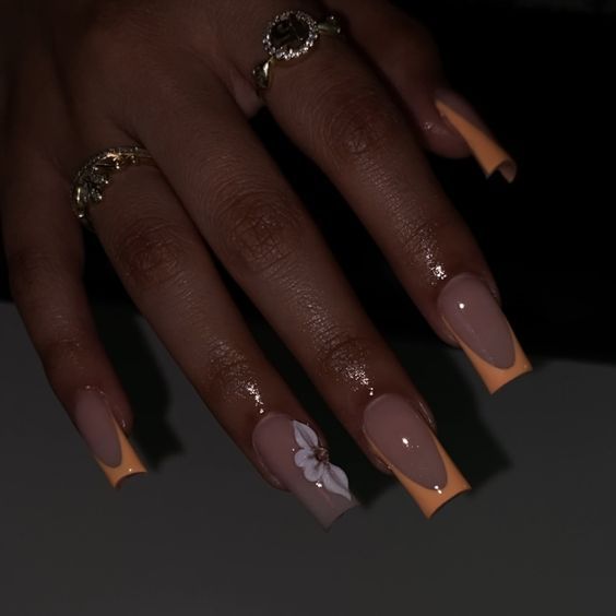 Chic Long Square Nail Design: Nude and Vibrant Orange with Floral Accent for Fashionable Elegance.