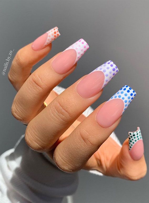 Chic and Whimsical Nail Design: Soft Nude Base with Vibrant Pastel Polka Dot Tips.