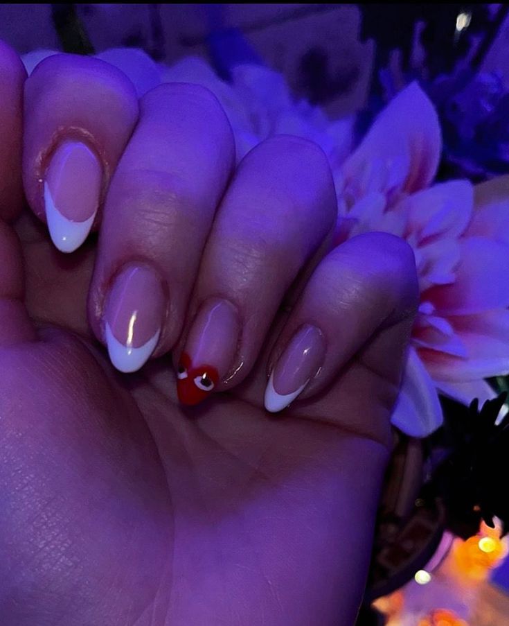 Chic Nail Design: Elegant White Tips with Playful Red Heart Accent.