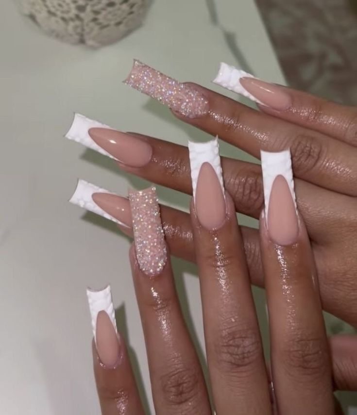 Elegant Nude and Sparkling Accented Nail Design with Glossy Finish and Unique White Tips.