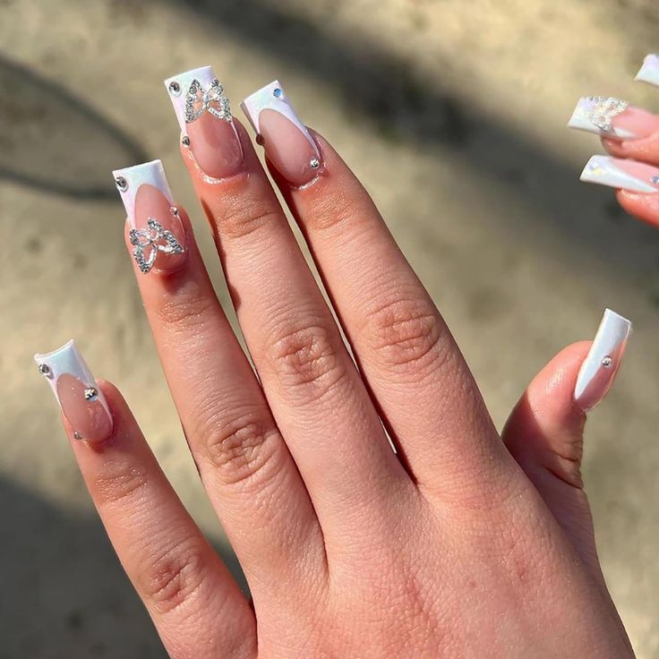 Sophisticated Long Nail Design with White Tips, Soft Pink Accents, and Glamorous Silver Embellishments.