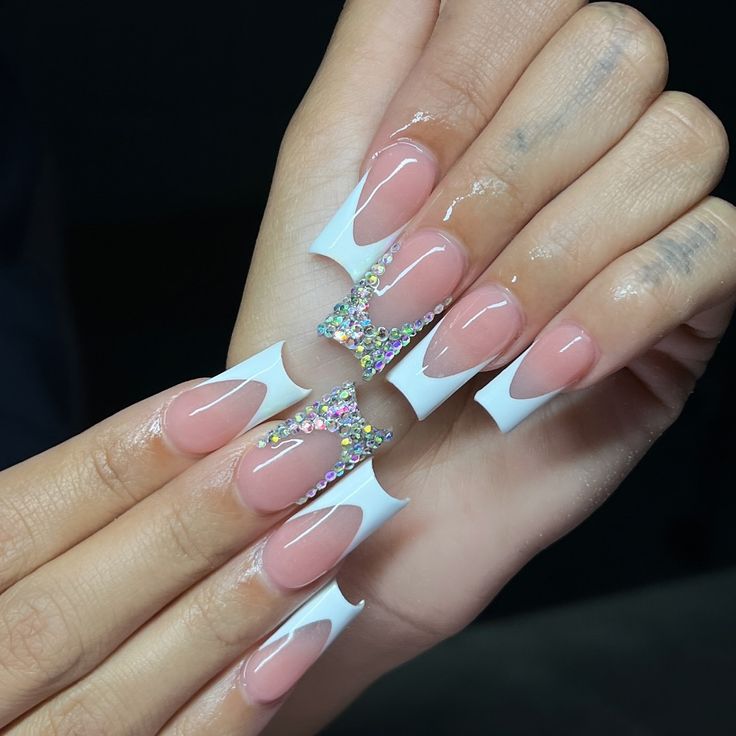 Chic Nail Design: Glossy Nude and White French Tips with Rhinestone Accents.